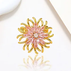 Detailed close-up of a floral brooch with pink marquise crystals and golden metal finish