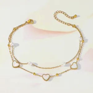 Close-up of double-layer gold anklet with heart pendants and elegant pearls