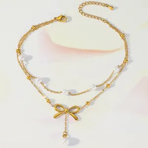 Detail of gold layered anklet featuring a small bow pendant and elegant white pearls