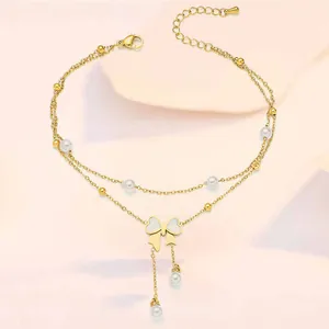 Detail of gold layered anklet featuring pearl accents and a butterfly bow tassel charm