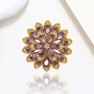 Detail of a rotating snowflake brooch with purple teardrop crystals on a gold-tone base