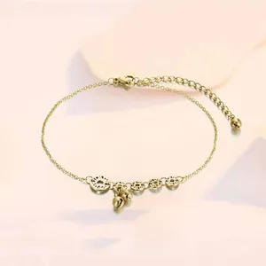 Detail of a gold-plated anklet featuring hollow circular charms and small bells
