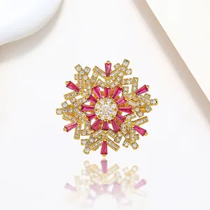 Macro detail of golden snowflake brooch with rose red crystals and shimmering pavé zircons