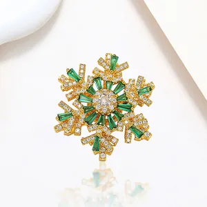 Close-up of golden snowflake brooch with green gemstones and micro-pave crystals