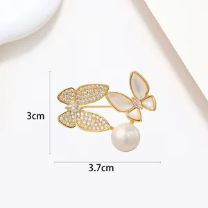 Close-up of golden butterfly brooch with zircon, shell texture, and white pearl details