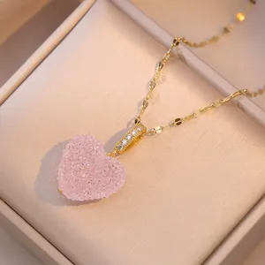 Close-up of pink crystal heart pendant with gold zircon-set clasp in velvet box