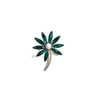 Elegant flower brooch with green crystals, white pearl center and gold plated stem