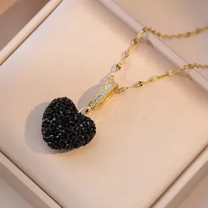 Macro shot of a black heart pendant with pavé crystals on a gold chain in a jewelry box