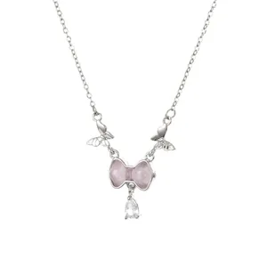 Primer plano de collar plateado con lazo rosa, mariposas y colgante de gota de cristal