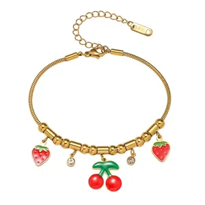 Bracelet en acier titane doré avec breloques fraises, cerises émaillées et cristaux