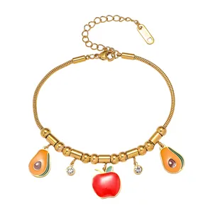 Détail du bracelet chaîne serpent en acier doré avec breloques avocat et pomme rouge