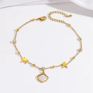Detail eines goldenen Fußkettchens mit Sternanhängern und schillerndem Muschel-Anhänger