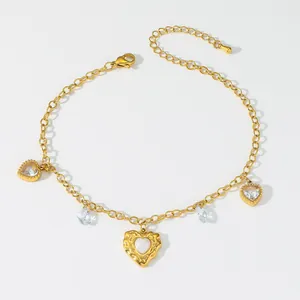Makroansicht des goldenen Fußkettchens mit Herzanhängern, Zirkon und Karabiner