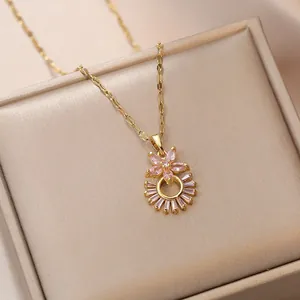 Collier avec gemme rose et fleur sur chaîne dorée posé sur une boîte à bijoux