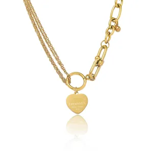Détail du pendentif cœur doré avec gravure sur un collier à maillons multi-rangs