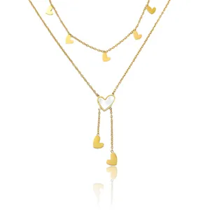 Détail du collier doré multicouche avec pendentif cœur en nacre et pampilles élégantes