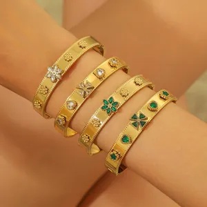 Stack of gold bangles with green and white zircons in vintage milgrain floral design