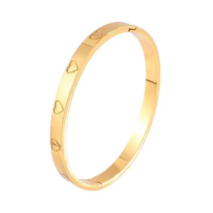 Elegant gold titanium steel hinged bangle featuring hollow heart patterns and polished finish