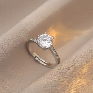 Macro shot of silver six-prong round solitaire ring with side stones on beige silk