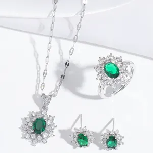Detailed set of silver emerald green necklace, ring, and earrings on white satin fabric