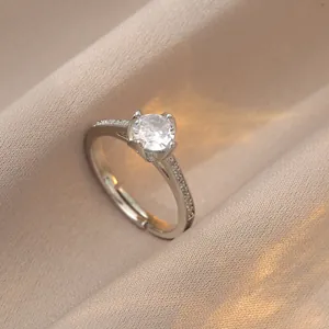 Close-up of 1 carat round zircon ring with side stones on champagne silk fabric