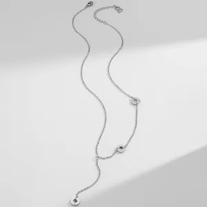 Silver Y-necklace detail showing three rings engraved with BEAUTY and a B letter tag