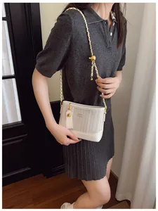Close-up of white tote bag with vertical fabric texture and golden adjustable chain strap