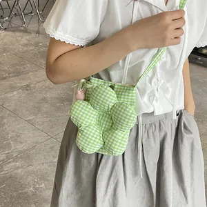 Green gingham crossbody bag with 3D floral decoration worn by a model in bright setting