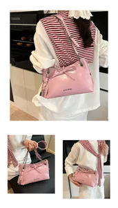 Close-up of pink glossy handbag featuring a leather bow and metal chain strap detail