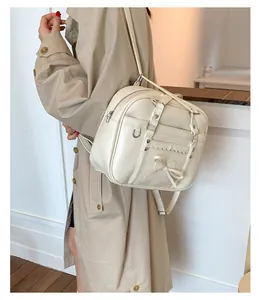 Dettaglio dello zaino color crema con fiocco in pelle PU e fibbie in metallo argento