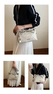 Detail of cream white tote bag featuring silver chain, bow decor and metallic lock