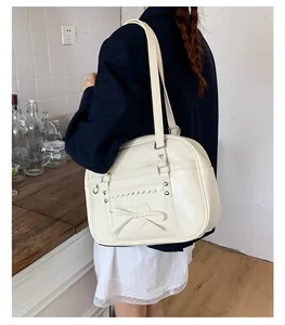 Dettaglio della borsa in PU crema con fiocco a cuore e fibbie in metallo indossata dal modello