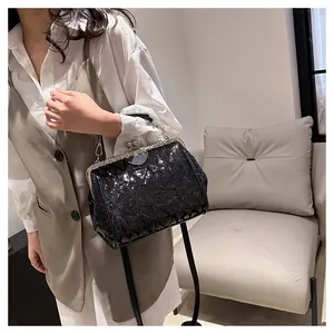 Détail d'un sac à bandoulière en paillettes noires avec fermoir métal et breloque cœur
