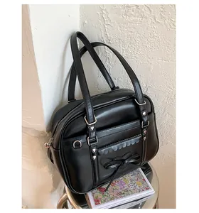 Dettaglio borsa nera stile JK con borchie a cuore, fiocco e bordo tasca ondulato