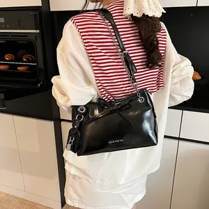 Black glossy tote bag with leather-chain strap and silver lock detail in a modern kitchen