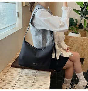 Close-up of CLEAR♥K black nylon hobo bag on shoulder showing texture and branded label