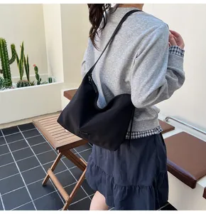 Side view of a black Hobo shoulder bag worn by a model in a minimalist setting