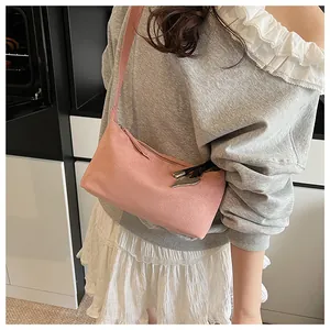 Detail of pink suede baguette bag with heart charm and tassel on a female model