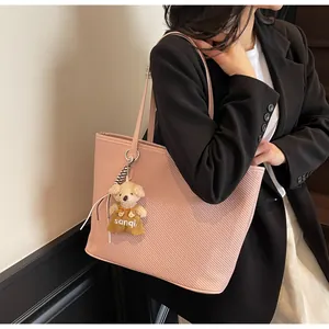 Detail of pink twill tote bag with bear charm and high-quality synthetic leather texture