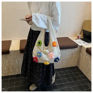Detail of white hollow-out knit tote bag featuring colorful 3D crochet flowers