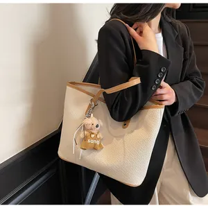 Detail of contrast stitch tote bag with teddy charm on a model in a black blazer