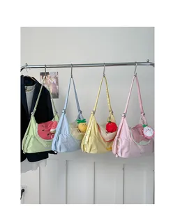 Detail of colorful fruit-themed tote bags in green, blue, yellow, and pink with plush charms