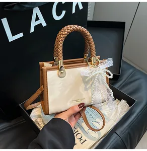 Detail of cream crossbody bag with woven handle and elegant pearl lace bow accessory
