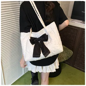 Detail der weißen Shopper-Tasche mit Seersucker-Struktur und großer schwarzer Satinschleife