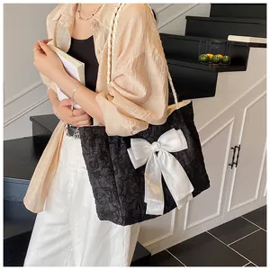 Detail einer schwarzen Falten-Tote-Bag mit großer weißer Satinschleife und Tragegurt