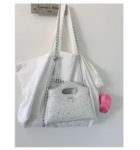 Close-up of white quilted handbag with crystal bow and pink plush heart charm