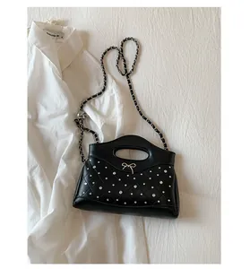 Detail of black quilted chain bag with rhinestone bow and metallic handle detail