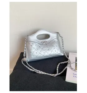 Detail of silver quilted handbag with metal bow and rivet accents on black knit
