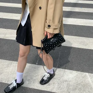 Quilted black crossbody bag with silver studs and bow on a city street crossing