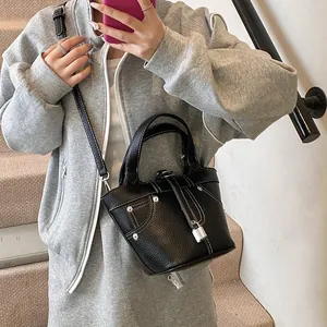 Sac seau noir minimaliste à motif litchi avec surpiqûres blanches et fermoir argenté